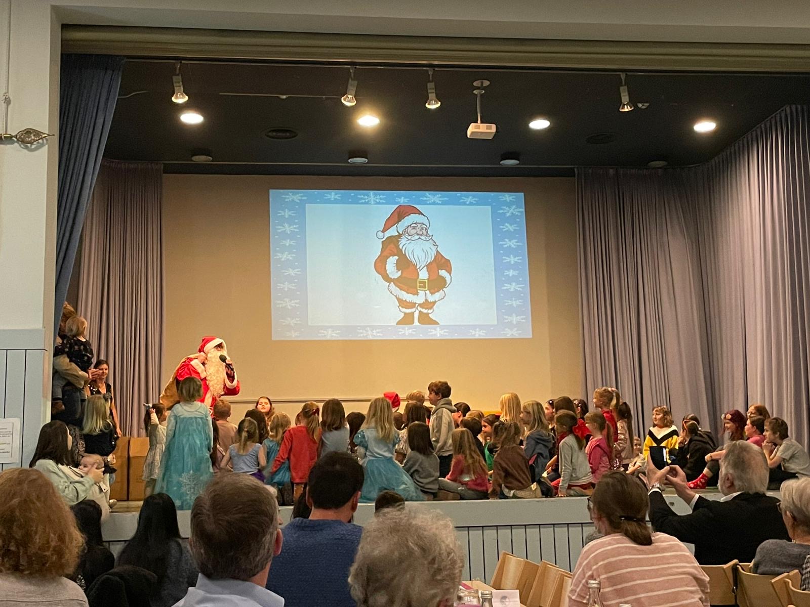 Der Nikolaus verteilt Schokolade an die Kinder des TVB auf der Bühne